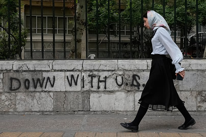 A woman walks past an anti-US graffiti painted on the wall of the Tehran University on Enqelab-e-Eslami street in downtown Tehran, Iran, Saturday, April 25, 2026 Vahid Salemi/Copyright 2026 The AP. All rights reserved