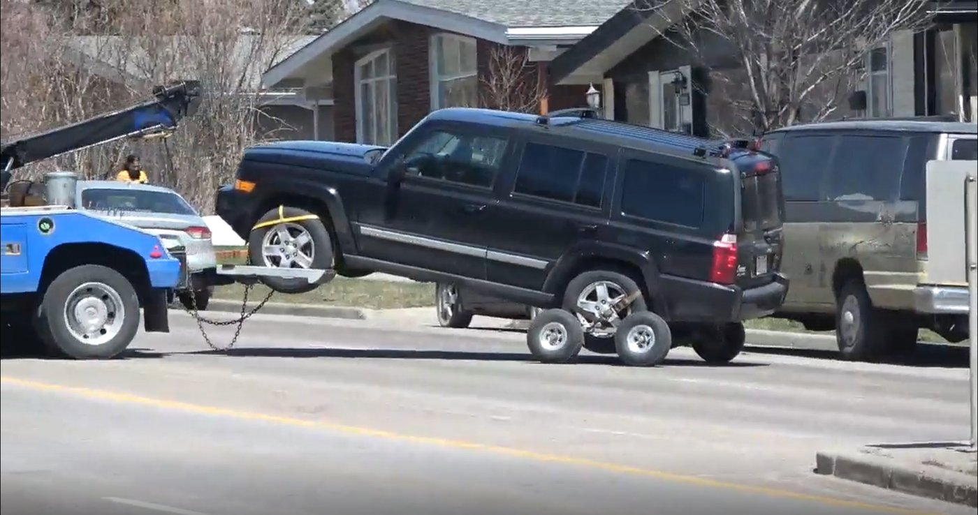 A vehicle where two children were found dead is being towed away as police watch the scene in Calgary on Thursday April 30, 2026. Police say a man is in custody after two children were found dead in a vehicle. THE CANADIAN PRESS/Dayne Patterson