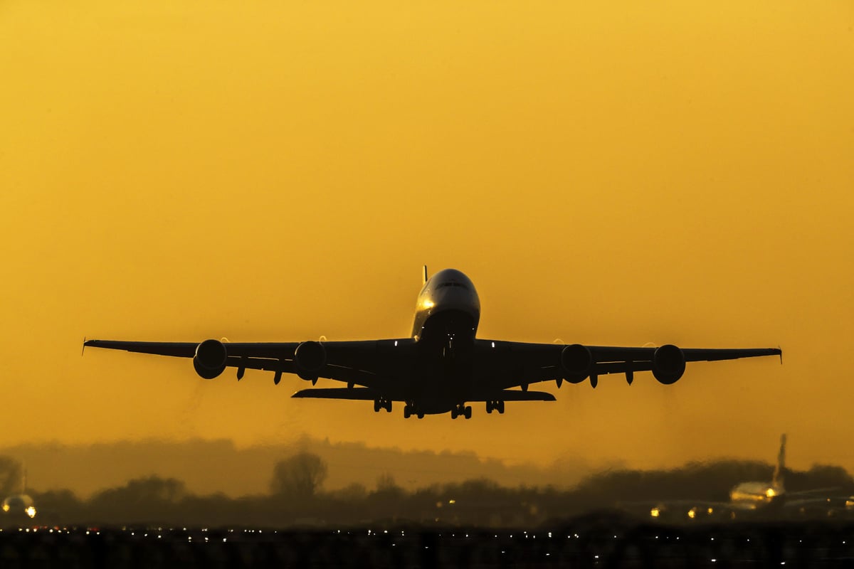 A plane takes off from Heathrow Airport against a golden hazy sky