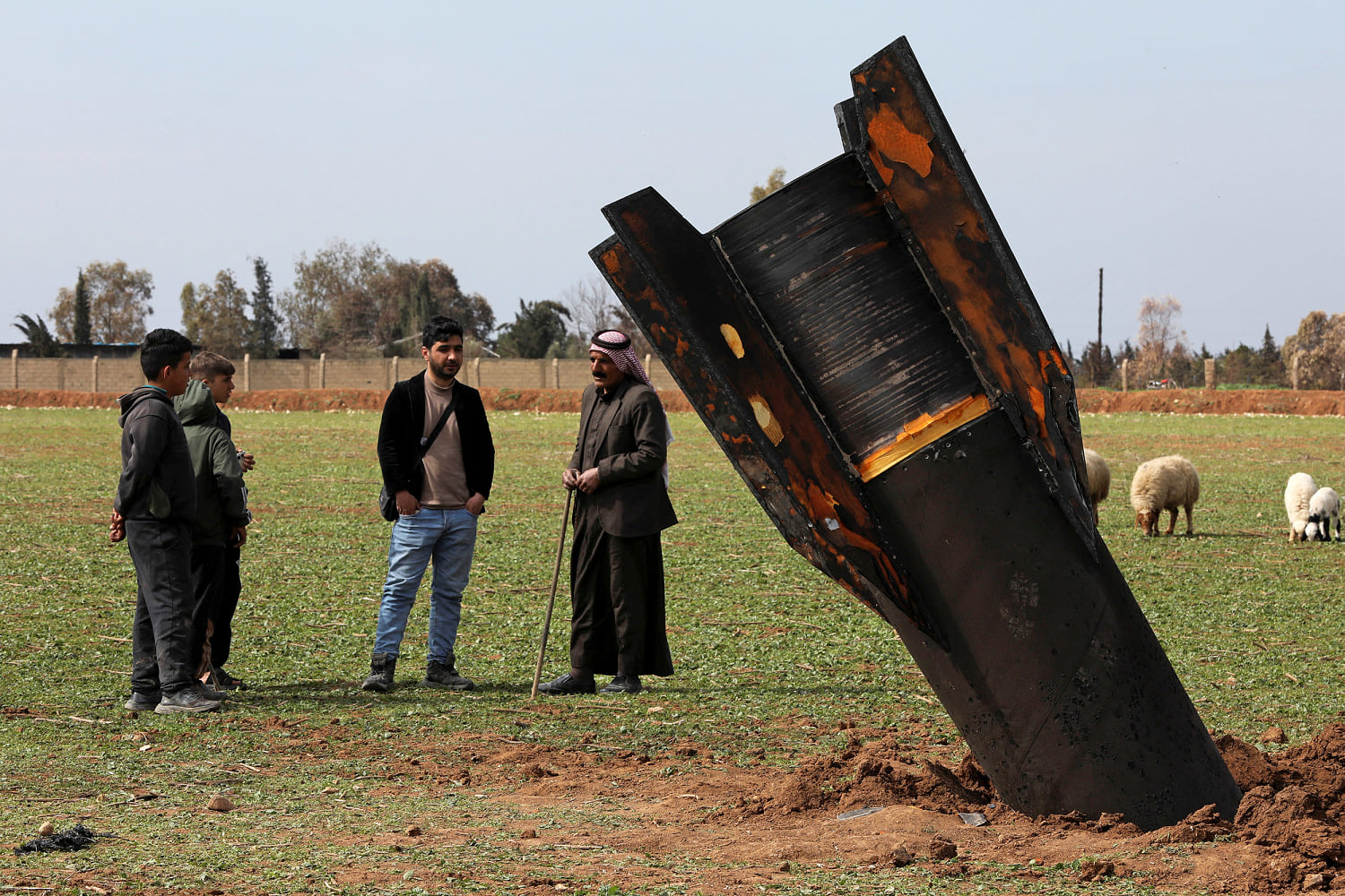 People stand next to an Iranian missile after it fell near Qamishli, Syria, on March 4. (Orhan Qereman / Reuters)
