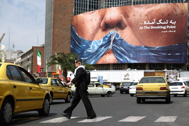 A woman walks past an anti-U.S. billboard depicting U.S. President Donald Trump and the Strait of Hormuz, in Tehran, Iran, May 2, 2026. Majid Asgaripour/WANA (West Asia News Agency) via REUTERS