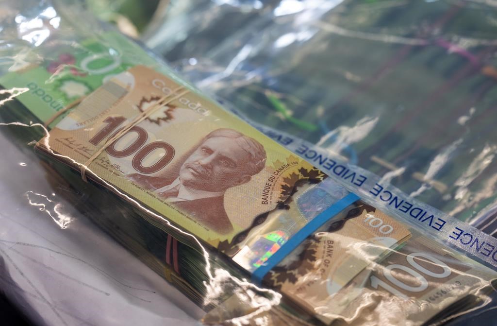 Money seized by police during a bust is displayed at RCMP headquarters In Surrey, B.C., on Dec. 7, 2022. THE CANADIAN PRESS/Jonathan Hayward