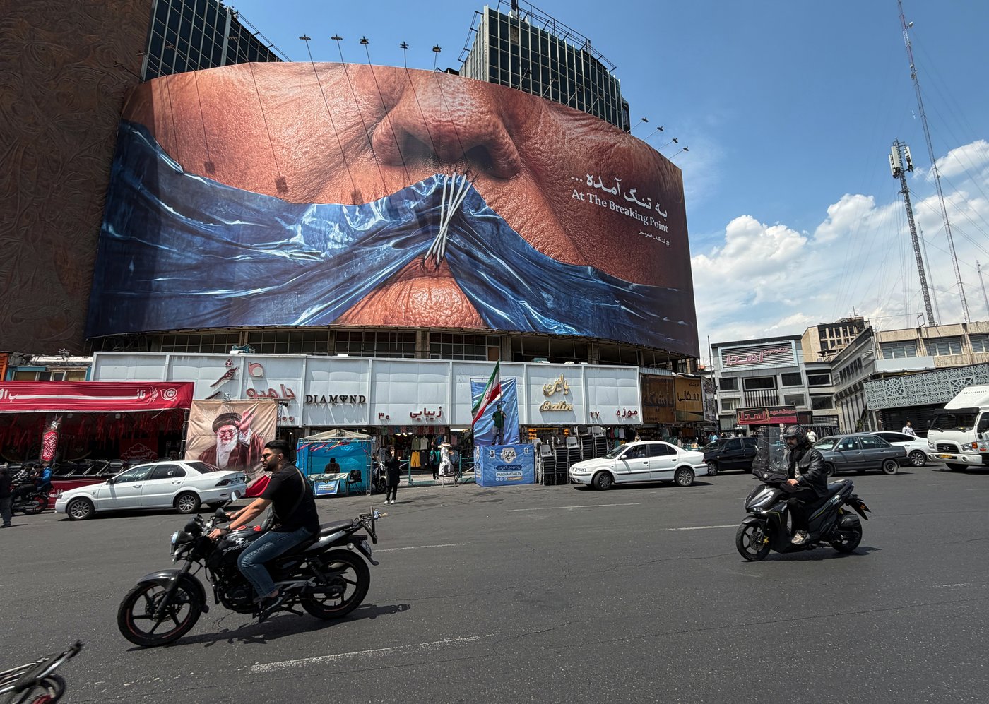 Vehicles drive past a billboard with graphic showing Strait of Hormuz and sewn lips of U.S. President Donald Trump in a square in downtown Tehran, Iran, Saturday, May 2, 2026. (AP Photo/Vahid Salemi)